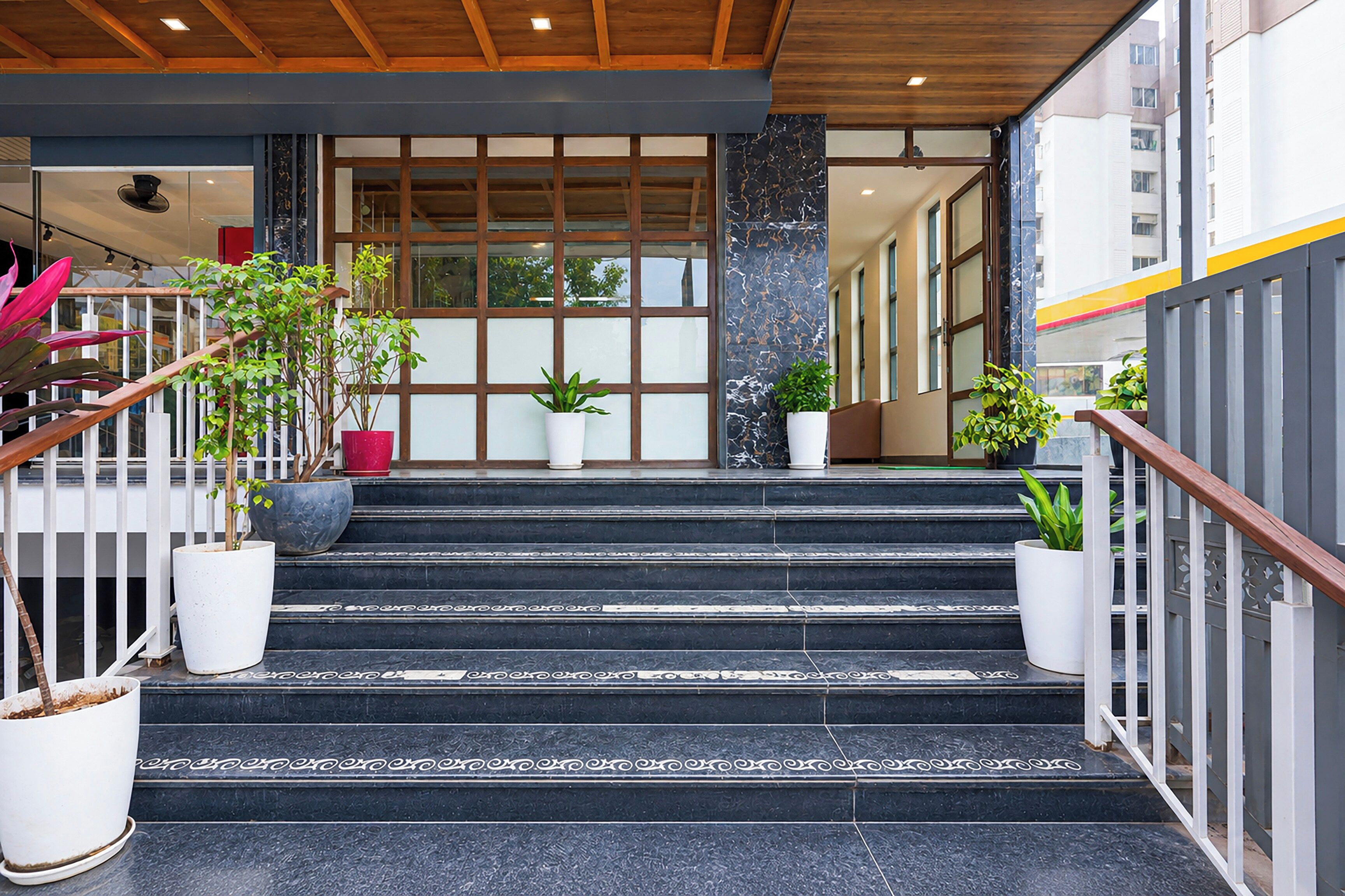 A staircase leading to a building entrance with potted plants on either side.