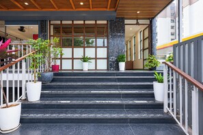 Una escalera conduce a la entrada de un edificio, con macetas a ambos lados.
