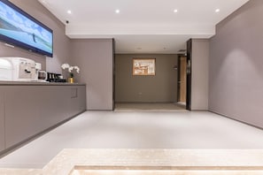 Un moderno hall de hotel con una máquina de café, un televisor de pantalla plana y un mapa digital en la pared.