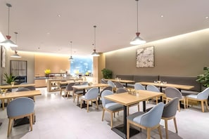 Un interior de restaurante moderno con varias mesas y sillas, una zona de bar y vistas a la ciudad.