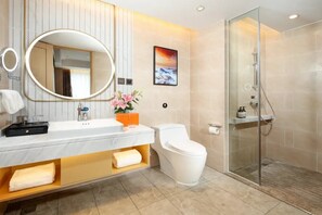 Un baño moderno con tocador de mármol, inodoro, cabina de ducha de cristal y un cuadro en la pared.