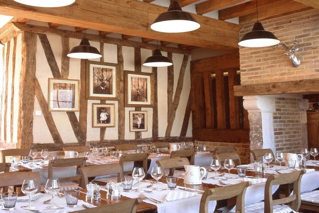 A restaurant interior with wooden beams, framed pictures on the wall, and tables set for dining.