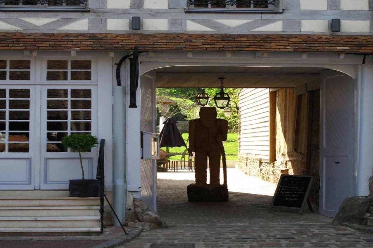 A building entrance with a statue, a signboard, and a window with shutters.