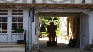 A building entrance with a statue, a signboard, and a window with shutters.