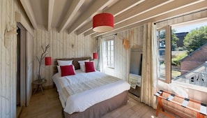 A bedroom with a large bed, a wooden ceiling, and a view of the outside. - Hotel Du Grand Cerf & Spa (Lyons-la-Foret)