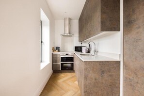 Una cocina moderna con horno integrado, microondas y campana extractora de acero inoxidable.