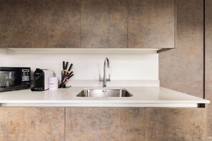 Una cocina moderna con un lavamanos de acero inoxidable, un microondas y una cafetera.