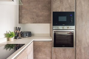 Una cocina moderna con microondas y horno integrados, una encimera con un tostador y una planta en maceta.