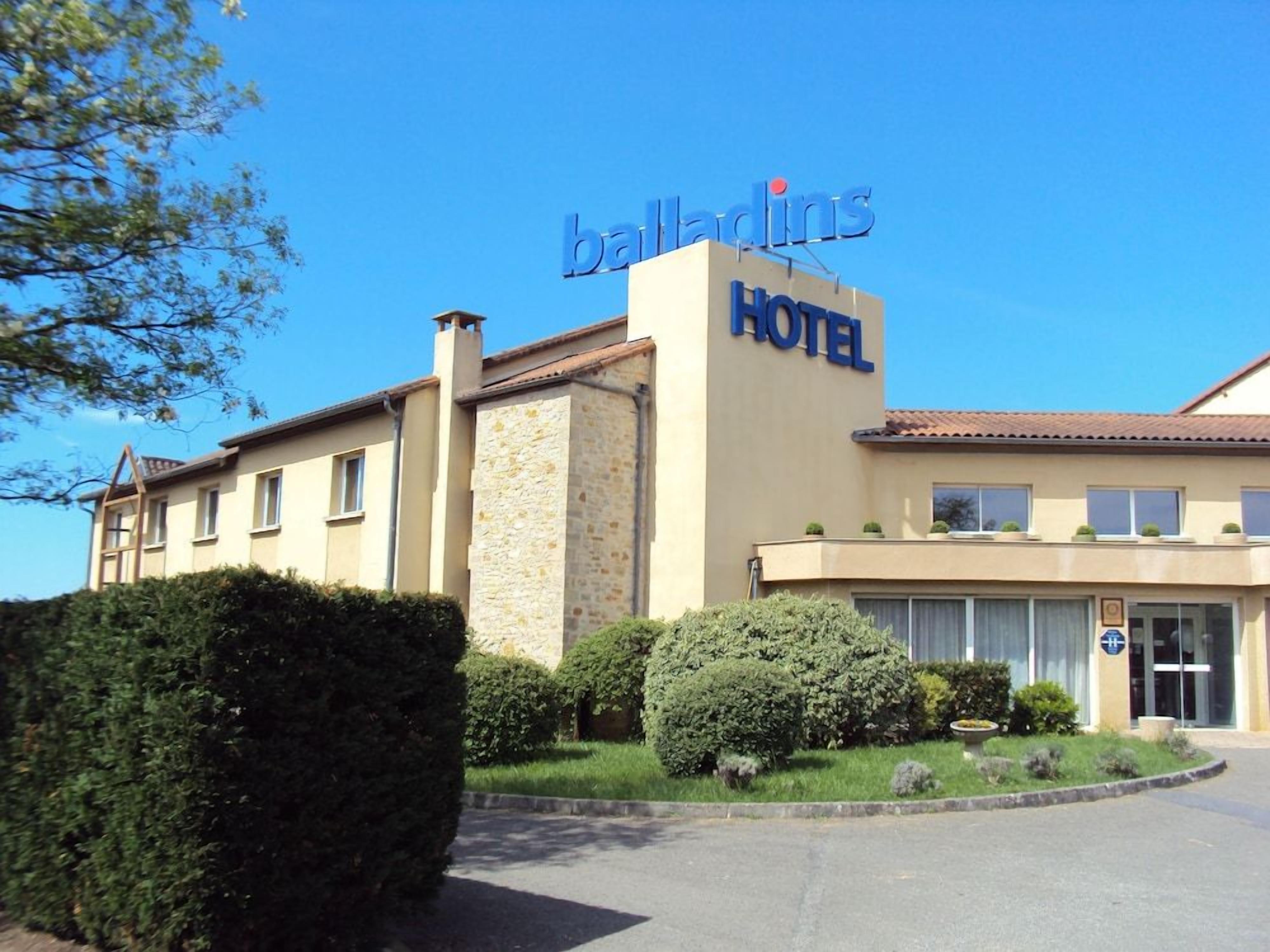 A hotel with a sign reading 'balladins HOTEL' and a clear sky.