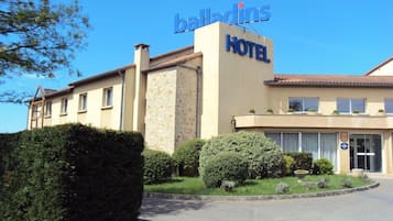 A hotel with a sign reading 'balladins HOTEL' and a clear sky.