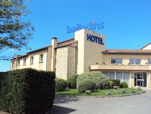 Um hotel com uma placa indicando 'balladins HOTEL' e um céu claro.