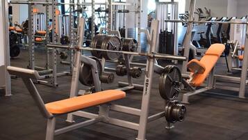 A gym with weightlifting equipment, benches, and treadmills.