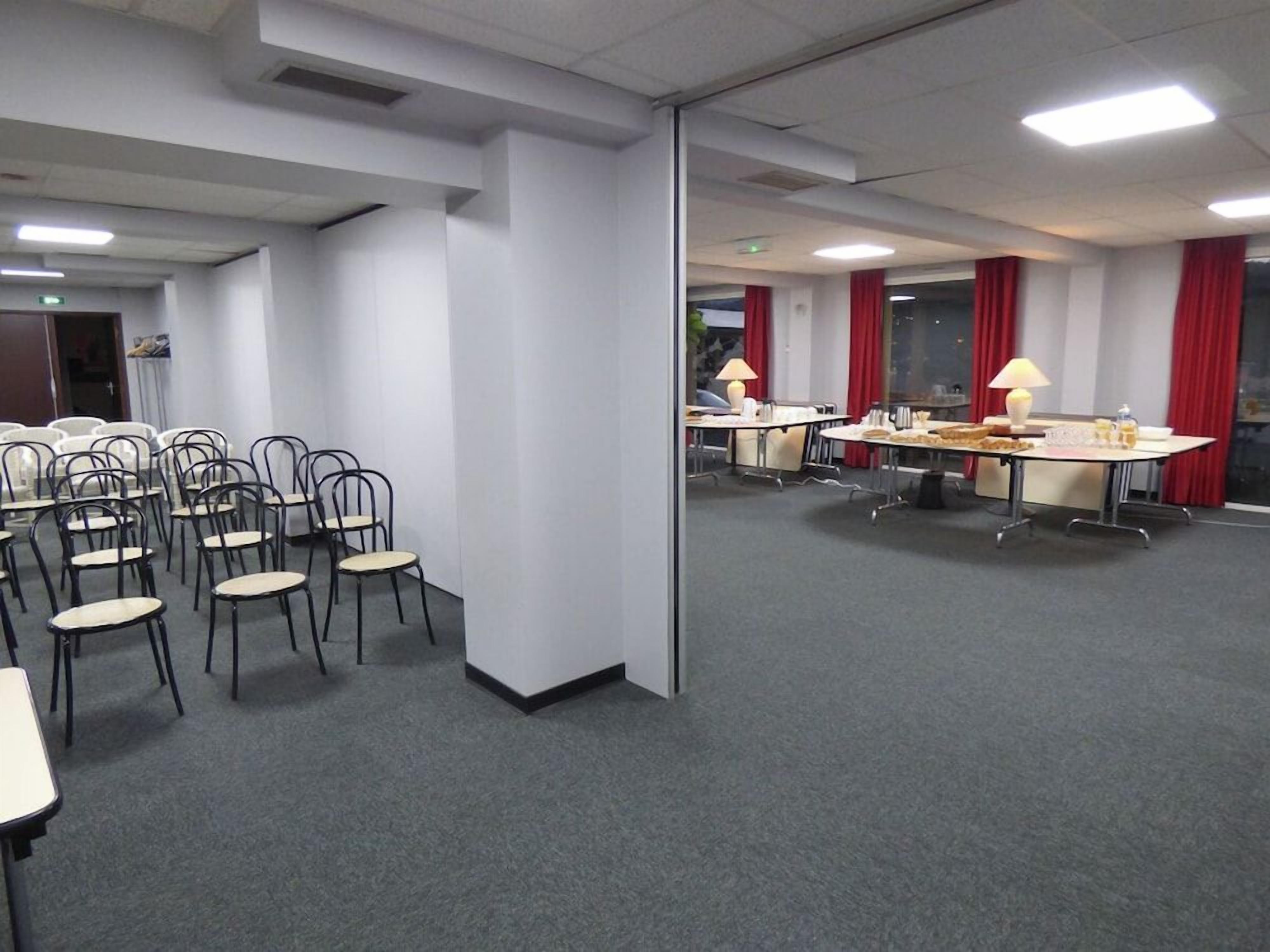 A conference room with tables and chairs, a glass partition, and red curtains.