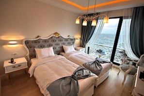 A double bed with a decorative headboard, bedside tables, a chair, and a view of the sea through a balcony.