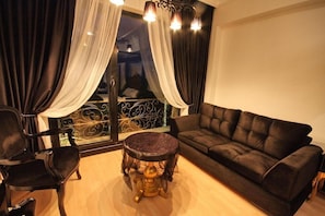 A living room with a black leather sofa, a round table with a marble top, and a chair.