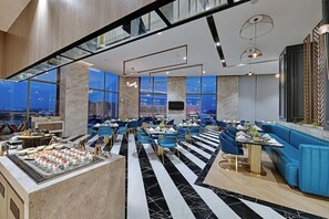 A modern hotel lobby with a high ceiling, marble flooring, and a city view. - The Fern Residency Gandhinagar (Gandhinagar)