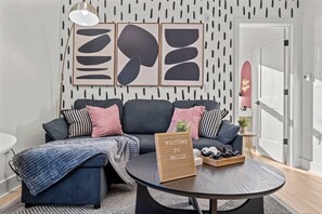 A modern living room with a sectional sofa, a coffee table, and a welcome sign.