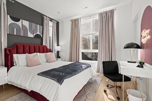 A modern bedroom with a large bed, a desk, and a chair.