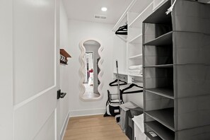 A hallway with a mirror, a coat rack, and a storage unit with shelves.