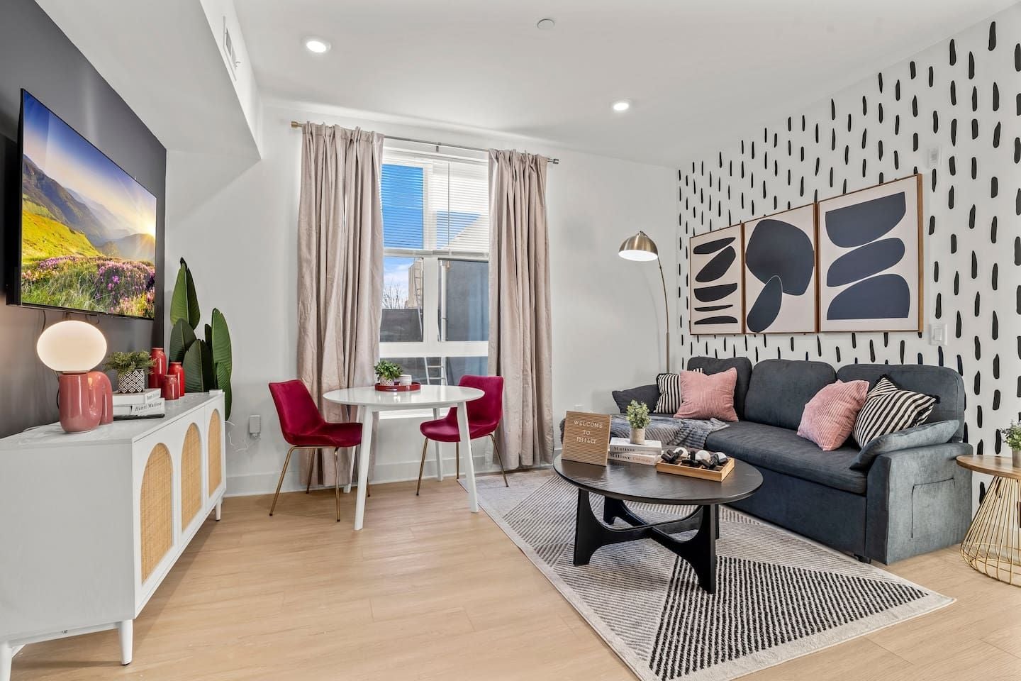 A modern living room with a sofa, a coffee table, a dining table with chairs, and a TV mounted on the wall.