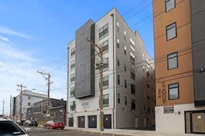 A multi-story building with a 'NOW LEASING' sign, indicating available rental space. - Designer Condo w Parking | Zoo, Museums • Center City (Philadelphia)