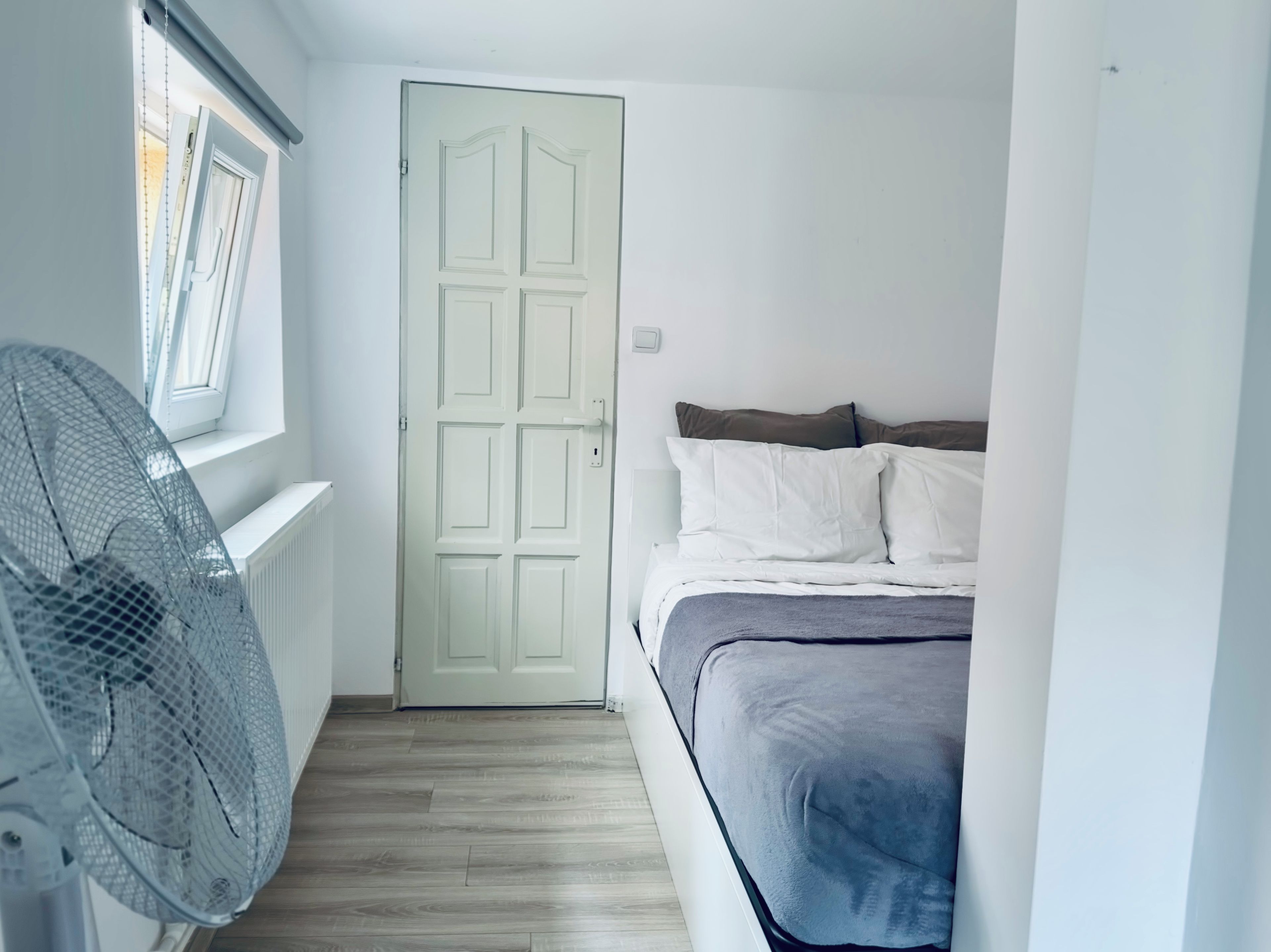 Un dormitorio con cama, ventilador y ventana con persianas.