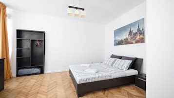 Un dormitorio con una cama, un armario, un cuadro y un suelo con estampado de espiga.