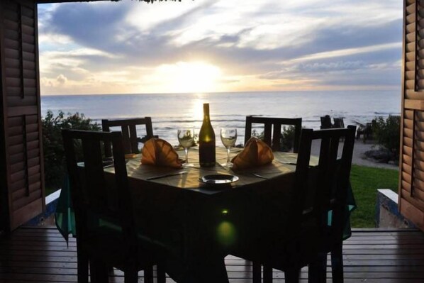 A table set for two with a bottle and glasses, overlooking a body of water.