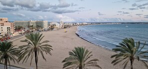 A beach with a row of buildings, palm trees, and a clear sky. - Apartamento con Espectaculares Vistas (Palma de Mallorca)