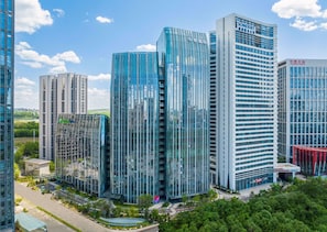 A cluster of modern high-rise buildings with reflective glass facades, surrounded by greenery and a clear sky. - Holiday Inn Express Changchun Ecological Square (Changchun)