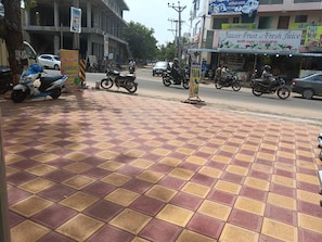 A street view with a tiled pavement, parked motorcycles, and a building with a signboard.