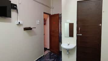 A hallway with a marble floor, a wooden door, a white sink, and a mounted television.