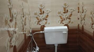 Un baño pequeño con inodoro, ducha y azulejos decorativos con motivos florales.