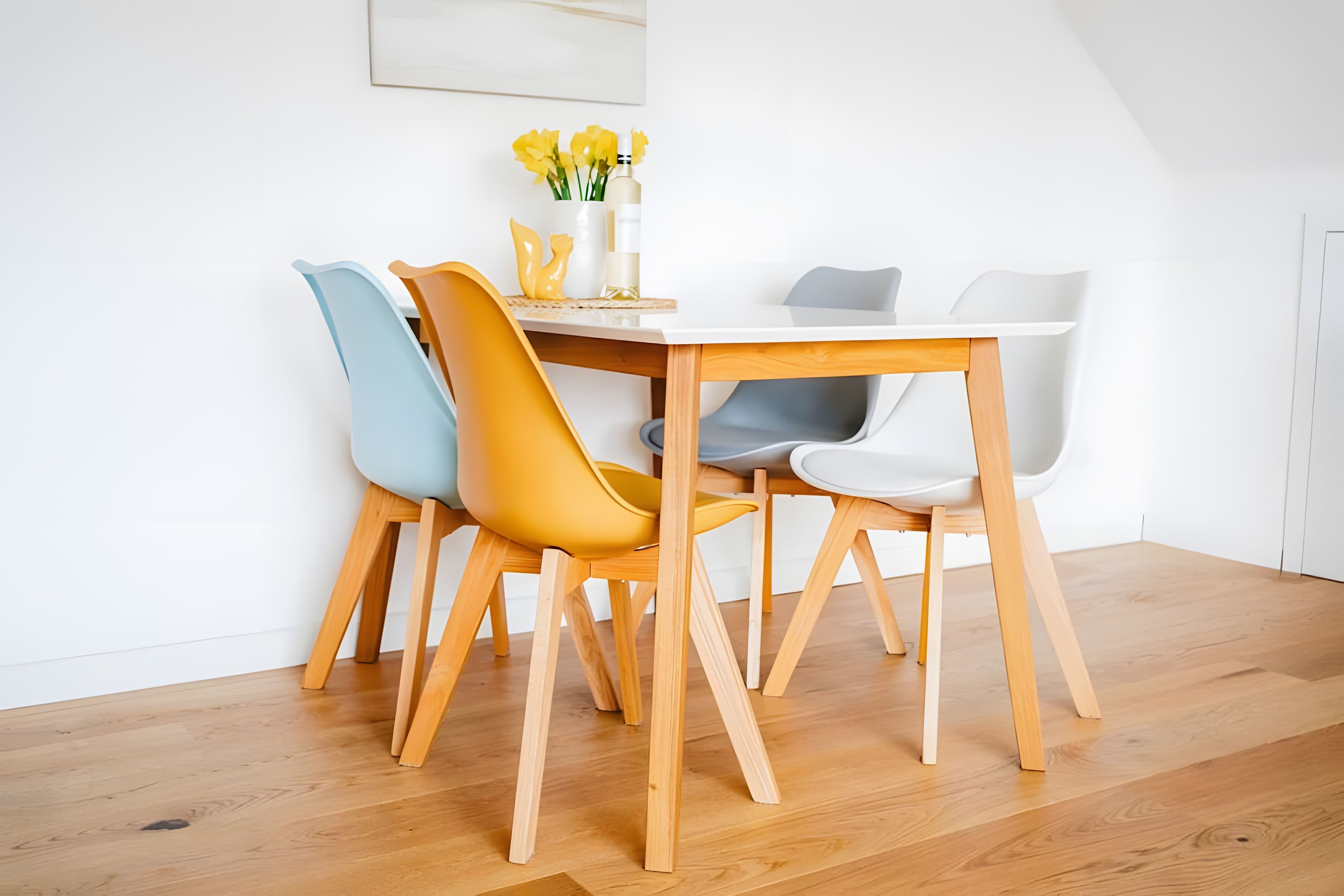 Un coin repas avec une table en bois et quatre chaises, dont une est jaune.