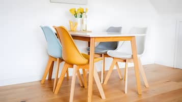 Un coin repas avec une table en bois et quatre chaises, dont une est jaune.