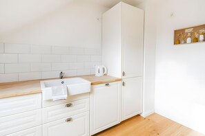 A modern kitchen with white cabinetry, a wooden countertop, and a built-in sink.