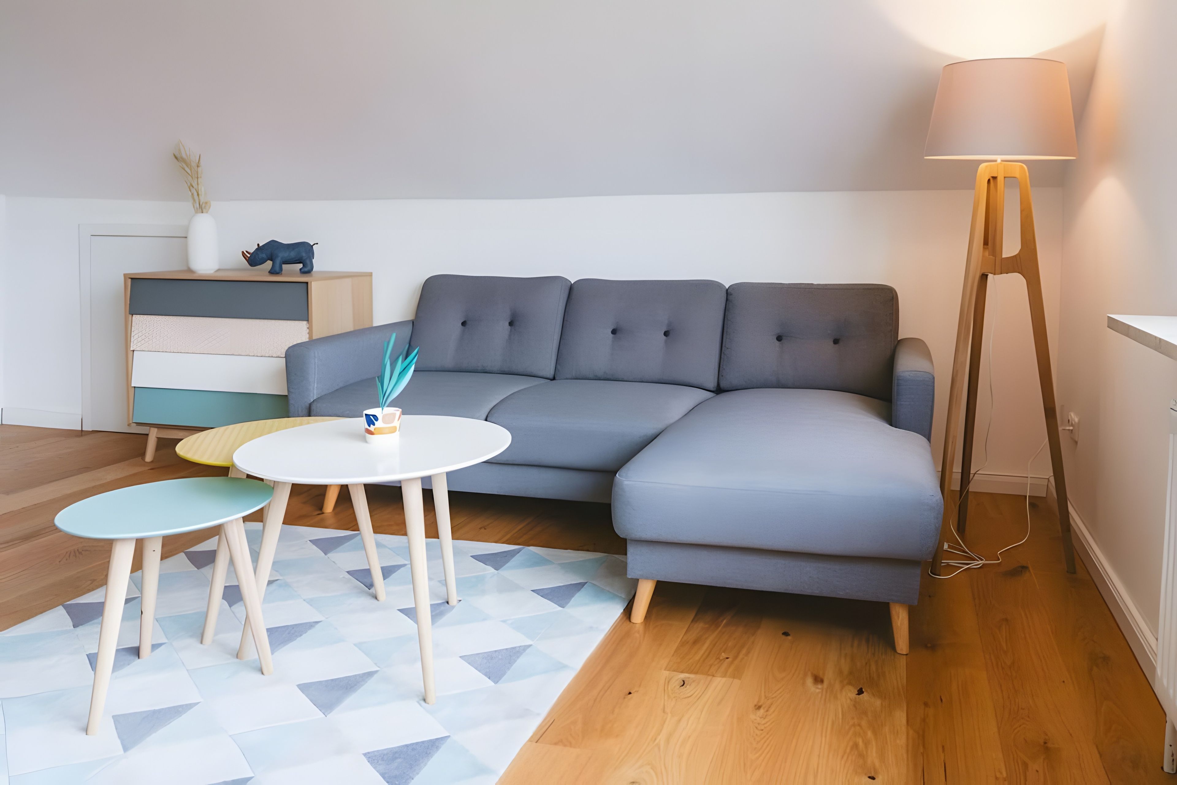 A modern living room with a grey sectional sofa, a small round table, and a floor lamp.