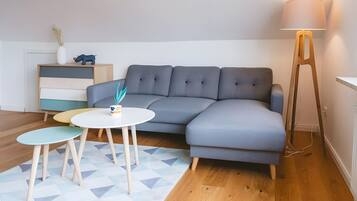 A modern living room with a grey sectional sofa, a small round table, and a floor lamp.