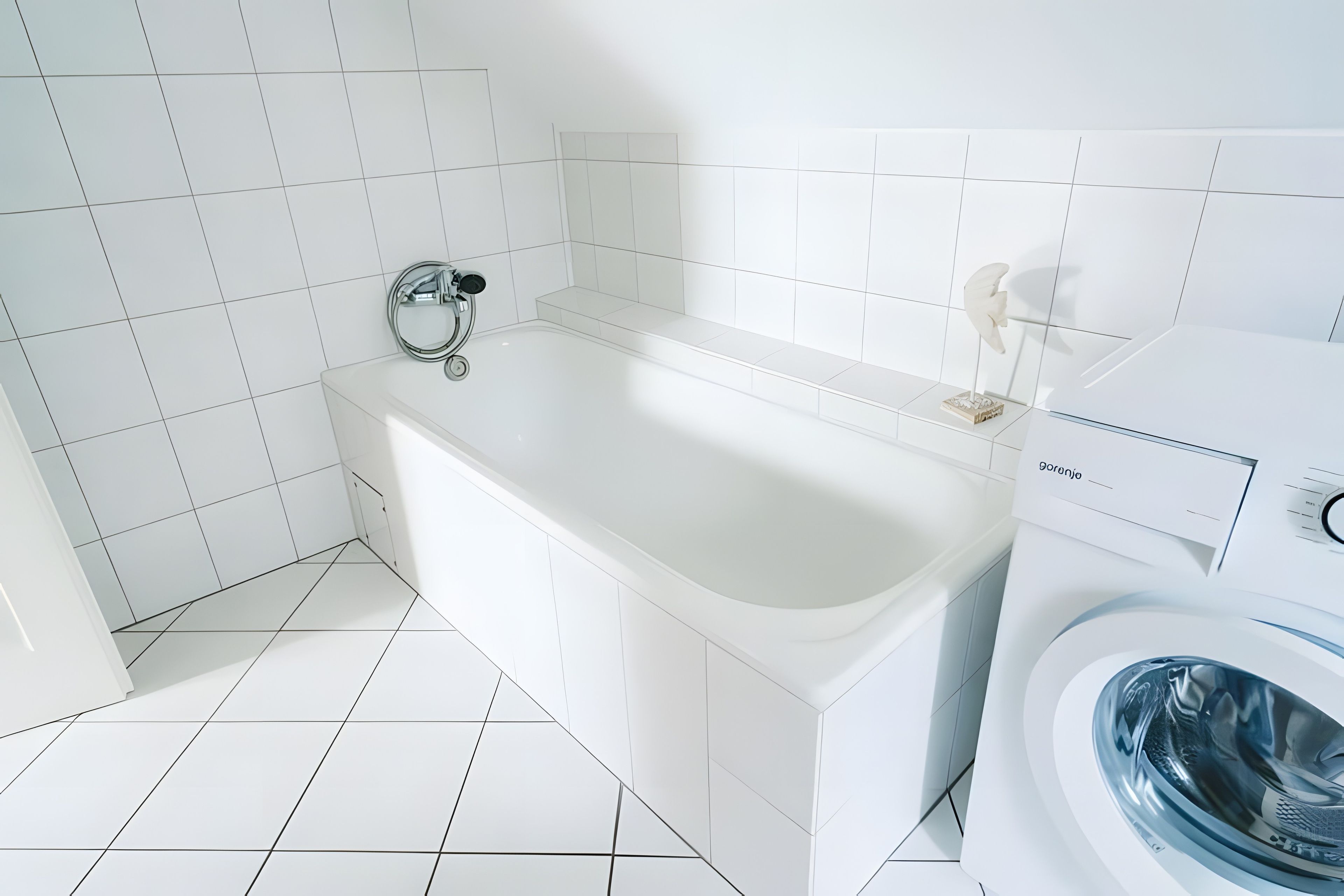 A modern bathroom with a white bathtub, a washing machine, and a toilet.