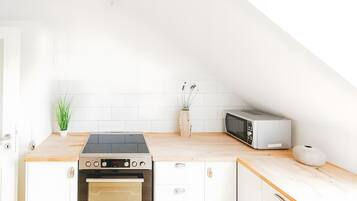 A modern kitchen with a built-in oven, a microwave, and a wooden countertop.