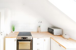 A modern kitchen with a built-in oven, a microwave, and a wooden countertop.