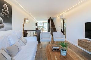 A modern living room with a sofa, two armchairs, a coffee table, and a TV. - An 1800s home in Combarro's historic quarter (Pontevedra)