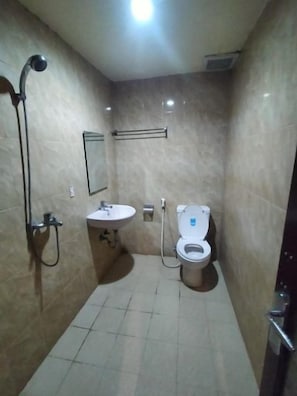 A small bathroom with a toilet, sink, and shower. - Hotel Bestskip Palembang (Palembang)
