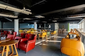 Un interior moderno con zonas de estar, mesas y una escalera visible.
