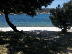 A beach with clear blue water, a sandy shore, and trees. - A2 - Modern apartment with garden, 80m from beach (Vinišće)