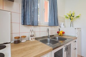 Una cocina moderna con dos lavamanos de acero inoxidable, una encimera de madera y un ventanal con cortinas a cuadros.