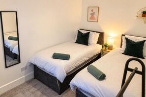 A twin room with two beds, a bedside table with a lamp, a mirror, and a framed picture on the wall. - Creswell 2-bed House, Sleeps 7 With Street Parking (Worksop)