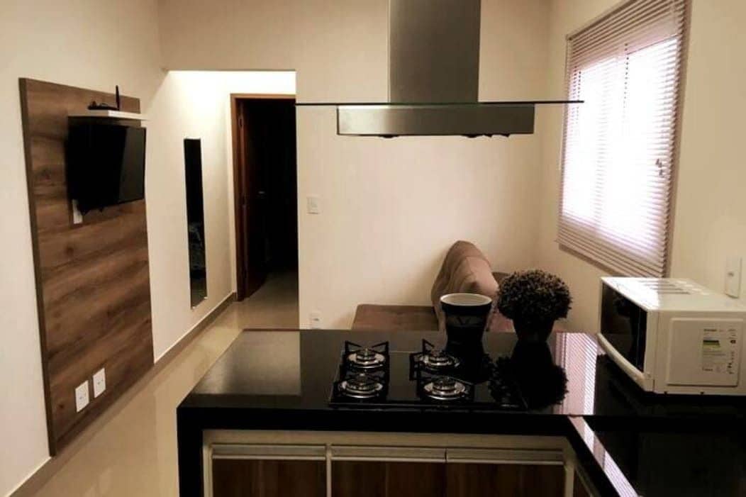 Cozinha compacta com fogão, micro-ondas e uma pequena mesa de jantar.
