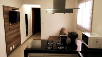 Cozinha compacta com fogão, micro-ondas e uma pequena mesa de jantar.