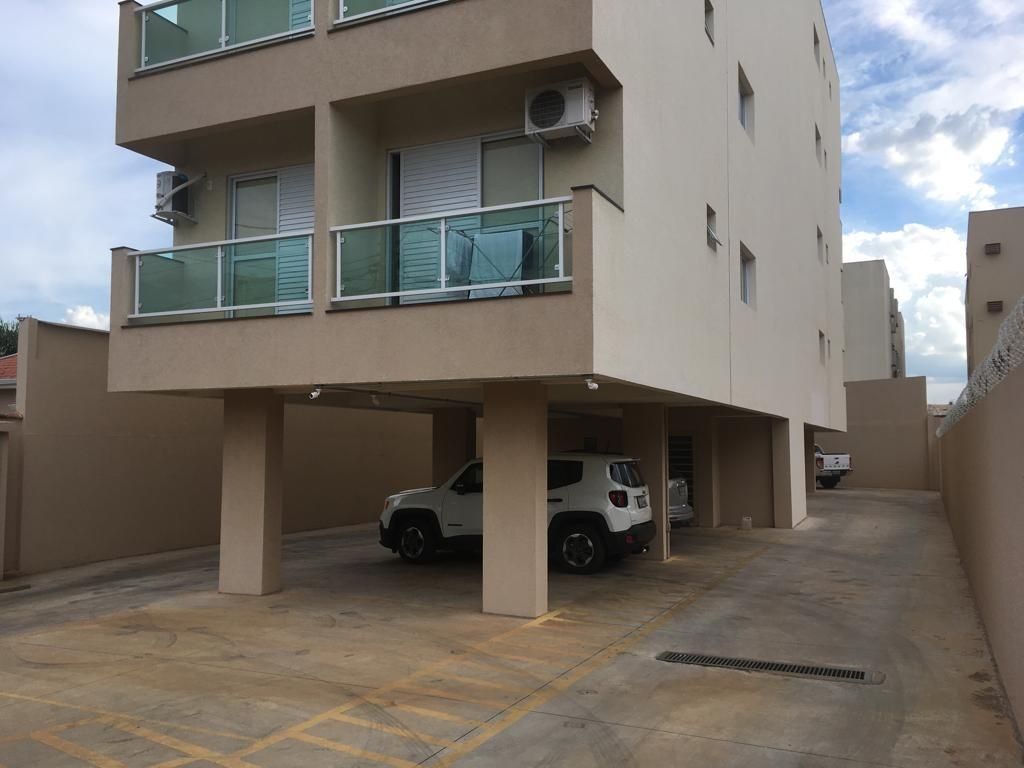 Um edifício de vários andares com garagem para carros. Dois SUVs brancos estão estacionados na garagem.